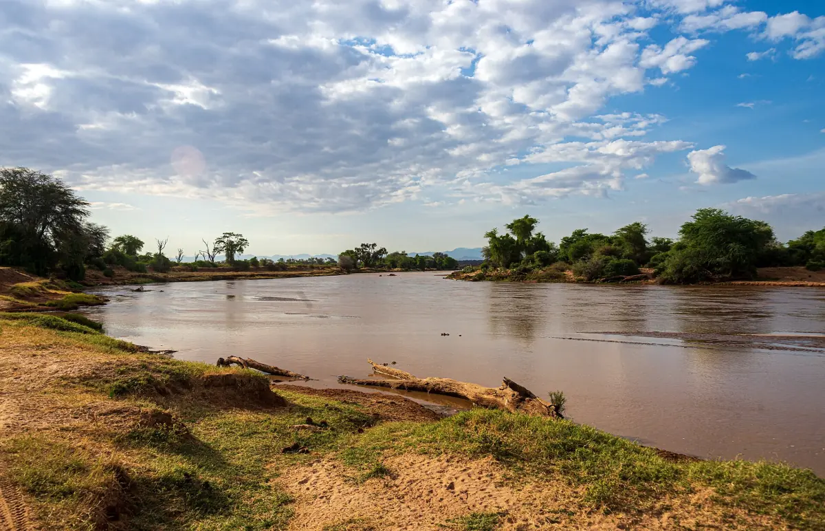 Biegung des braunen Flusses Ewaso Nyiro unter bewölktem Himmel in Samburu
