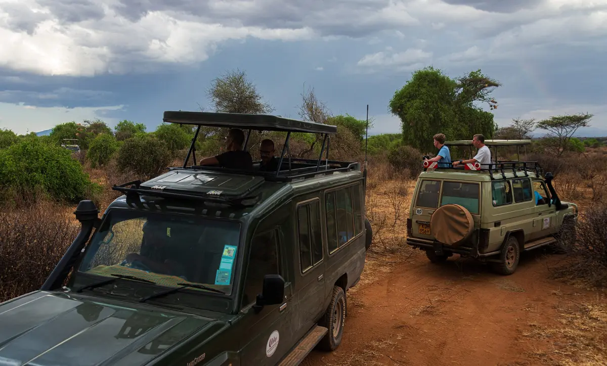 Two safari vehicles with open roofs on a dirt track in Samburu